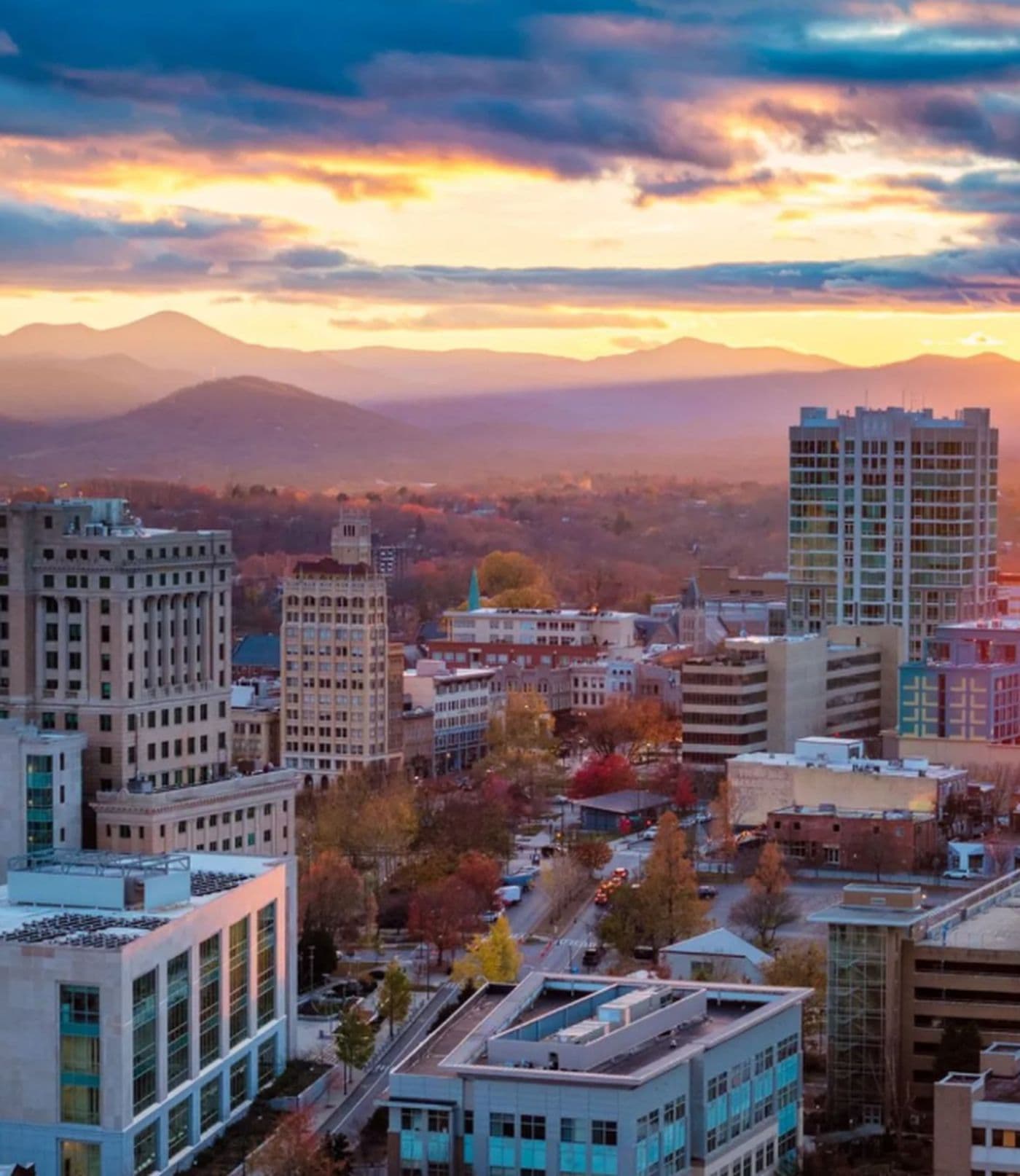 Downtown Asheville, North Carolina at sunset with the Blue Ridge Mountains behind it
