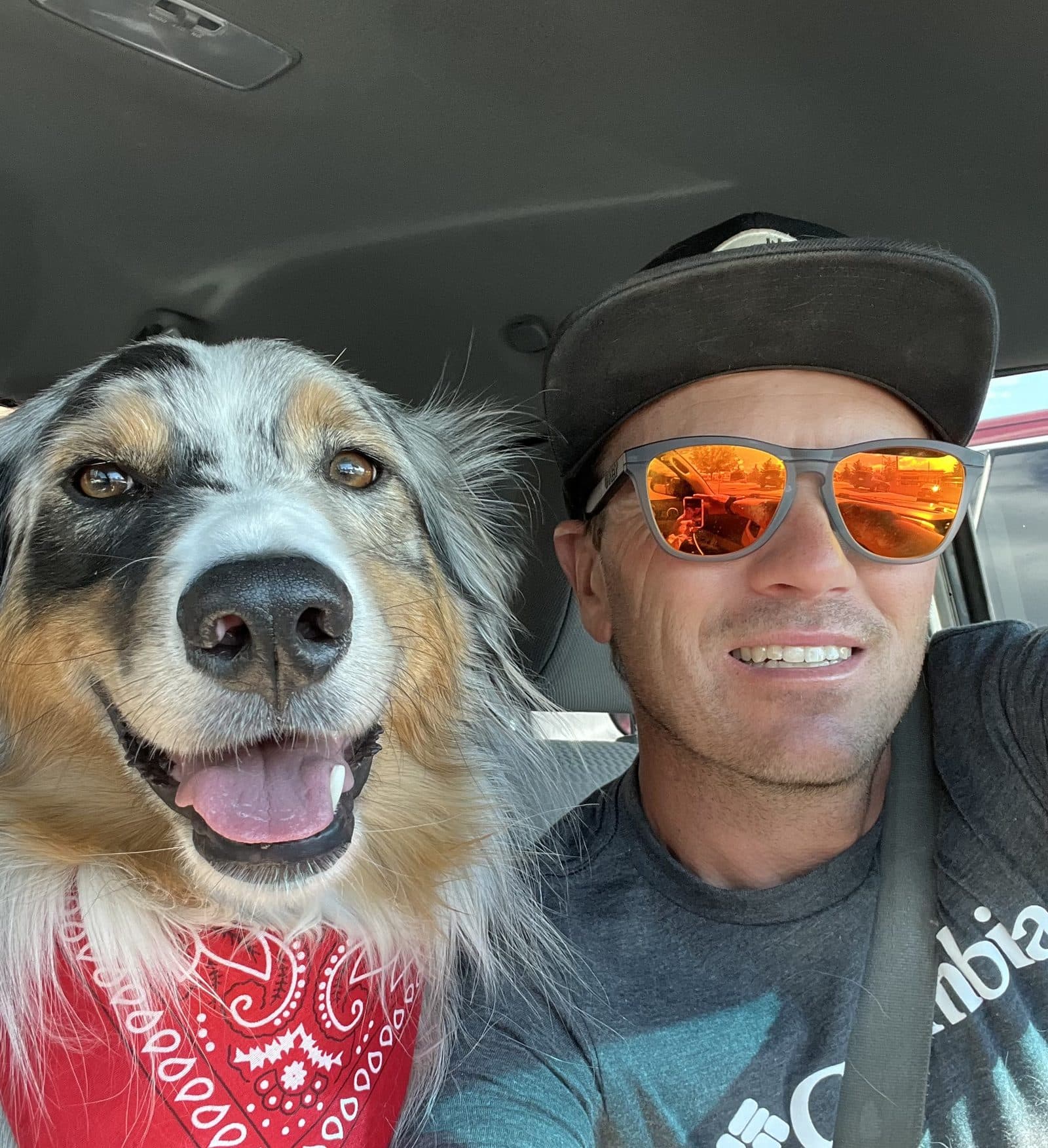 Joseph Caddel and his dog Bridger, wearing a red bandana, in the cab of a work truck