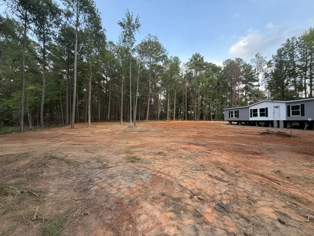 Cleared and graded lot with mature pines left standing and a new home set on its piers