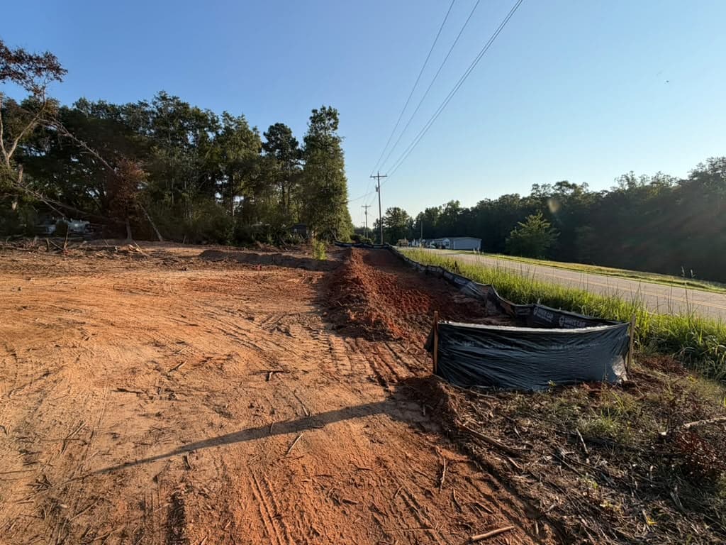 Cleared and rough-graded roadside lot with silt fence run along the road frontage