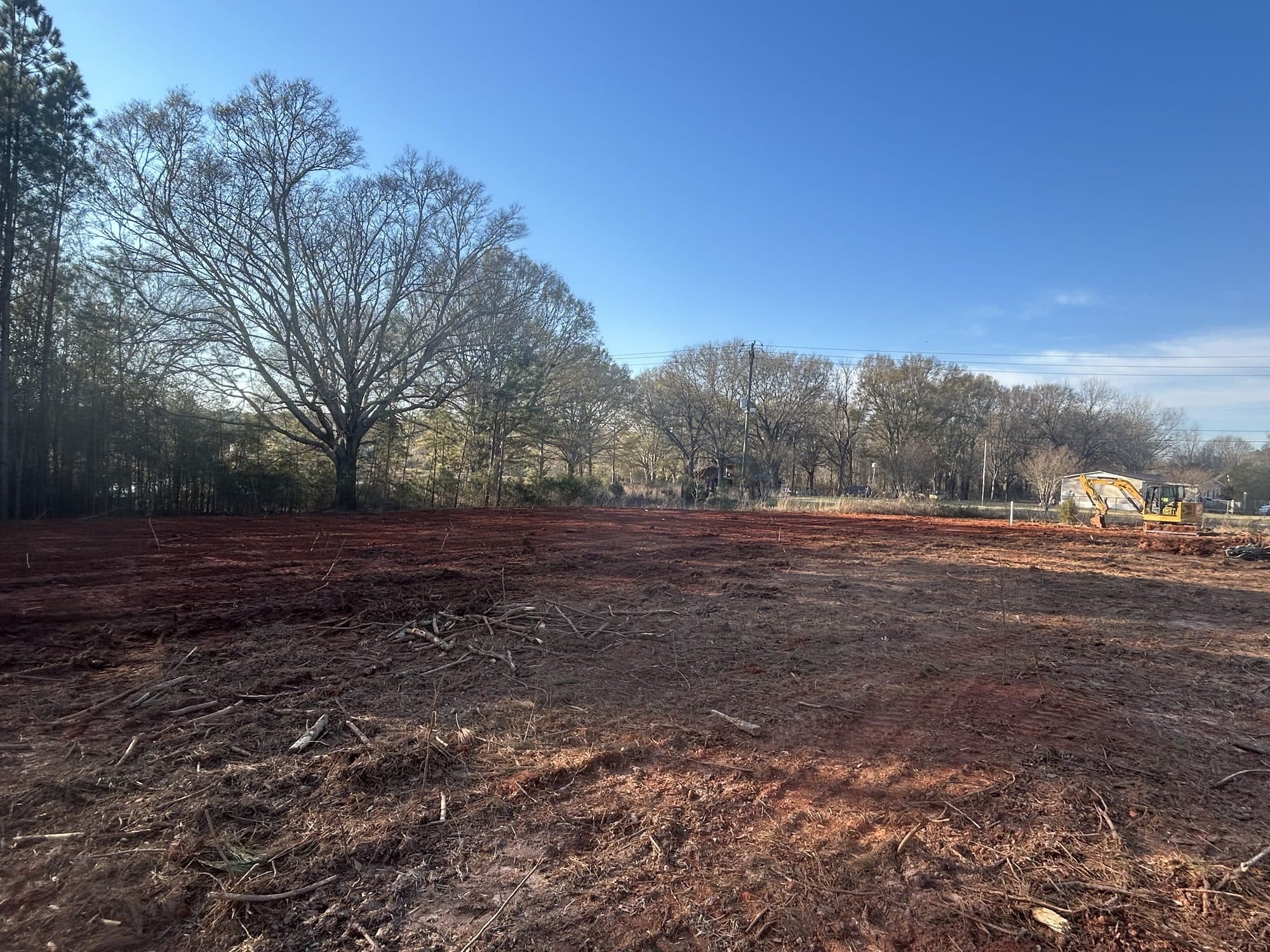 Freshly cleared and rough-graded building lot surrounded by trees