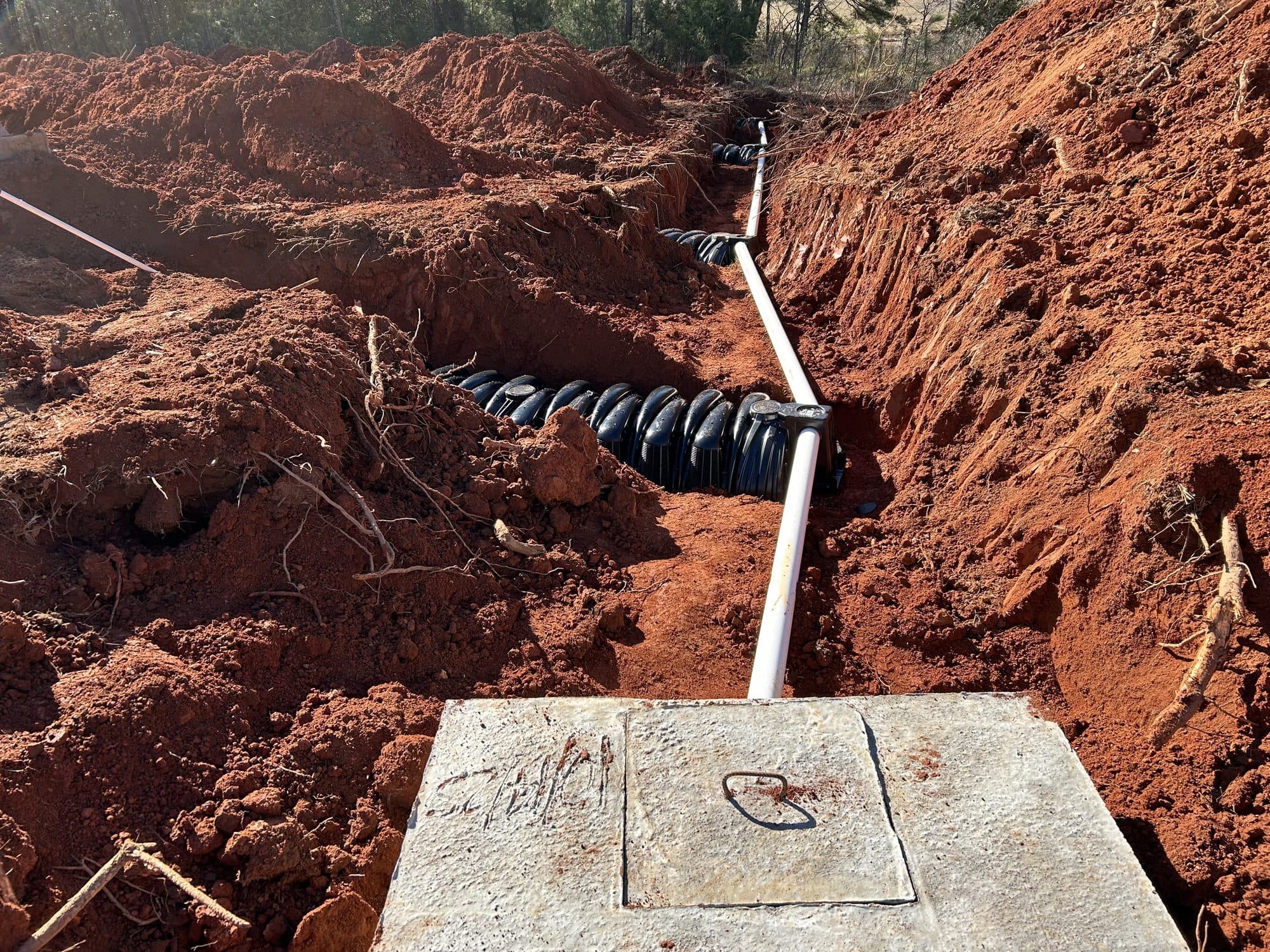 Septic distribution box and corrugated drain field pipe installed in an open trench